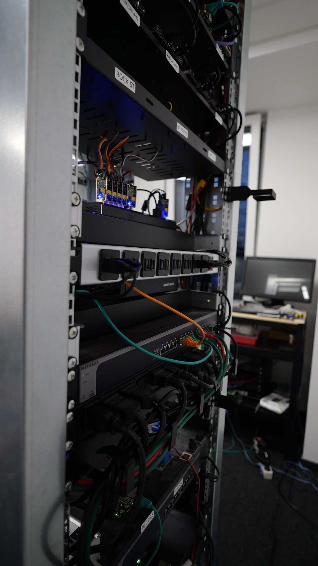 Side view of the lab rack: boards, SD-card switchers and USB serial consoles